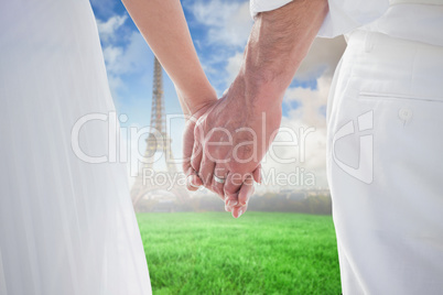 Composite image of bride and groom holding hands close up