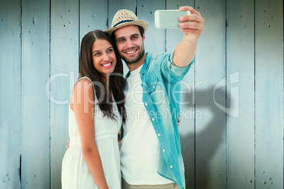 Composite image of happy hipster couple taking a selfie