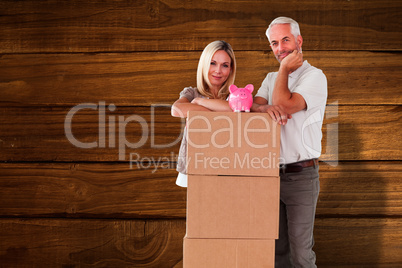 Composite image of happy couple leaning on pile of moving boxes