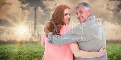 Composite image of casual couple standing arms around