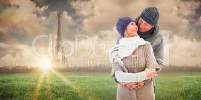 Composite image of happy mature couple in winter clothes embraci