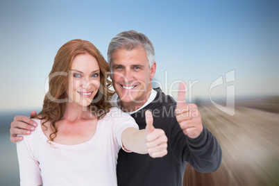 Composite image of casual couple showing thumbs up