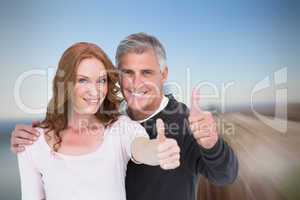 Composite image of casual couple showing thumbs up