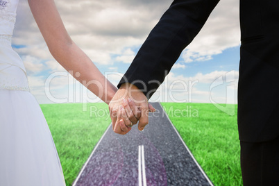 Composite image of mid section of newlywed couple holding hands