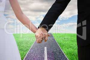 Composite image of mid section of newlywed couple holding hands