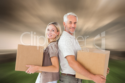 Composite image of happy couple holding moving boxes