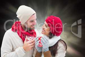 Composite image of winter couple holding mugs