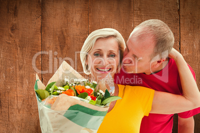 Composite image of mature man kissing his partner holding flower Composite image of mature man kissing his partner holding flower