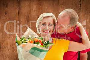 Composite image of mature man kissing his partner holding flower