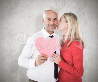 Composite image of handsome man holding paper heart getting a ki