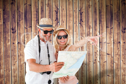 Composite image of happy tourist couple using map and pointing