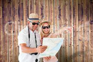 Composite image of happy tourist couple using map and pointing