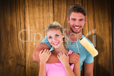 Composite image of young couple hugging and holding paint roller