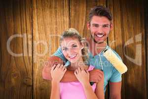 Composite image of young couple hugging and holding paint roller