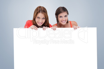 Composite image of teenage girls smiling while holding a blank p