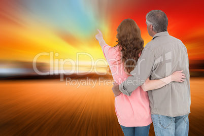 Composite image of casual couple standing arms around