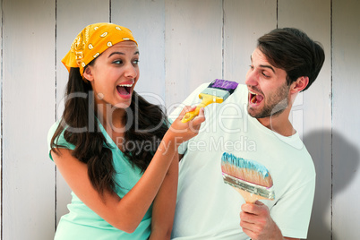 Composite image of happy young couple painting together and laug