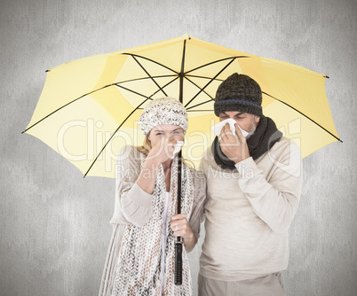 Composite image of couple in winter fashion sneezing under umbre