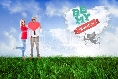 Composite image of cool couple holding a red heart together