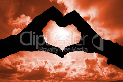 Composite image of couple making heart shape with hands