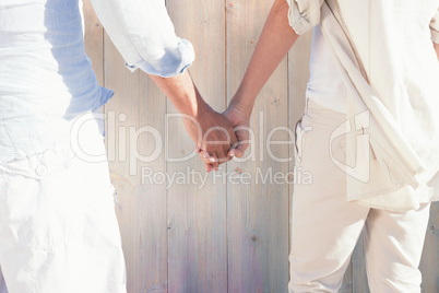 Composite image of couple on the beach looking out to sea holdin