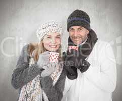 Composite image of happy couple in winter fashion holding mugs
