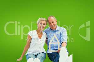 Composite image of happy mature couple holding a house shape