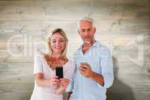 Composite image of happy couple texting on their smartphones