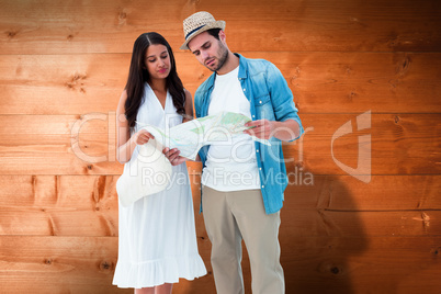Composite image of lost hipster couple looking at map
