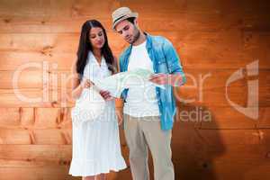 Composite image of lost hipster couple looking at map
