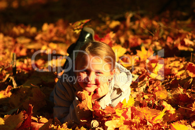 little girl laying in yellow leaves