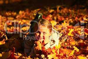 little girl laying in yellow leaves