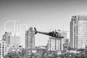 Black helicopter hovering over New York buildings