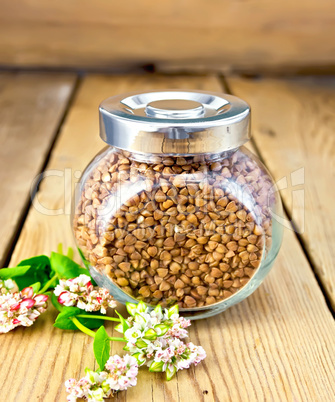 Buckwheat in glass jar and flower on board
