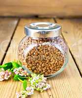 Buckwheat in glass jar and flower on board