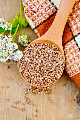 Buckwheat in spoon on board with flower and doily