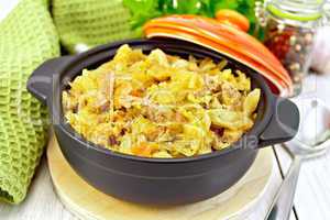 Cabbage stew with meat in black brazier on light board