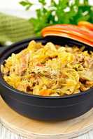 Cabbage stew with meat in black roaster on board