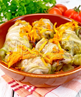 Cabbage stuffed and carrots in ceramic pan on board