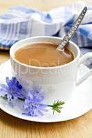Chicory drink in white cup with spoon and flower on board