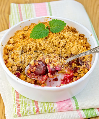 Crumble cherry in bowl with spoon on napkin