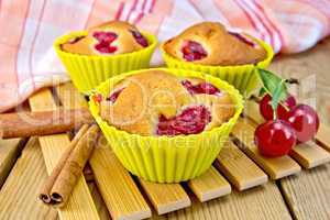 Cupcakes with cherries in tins on board