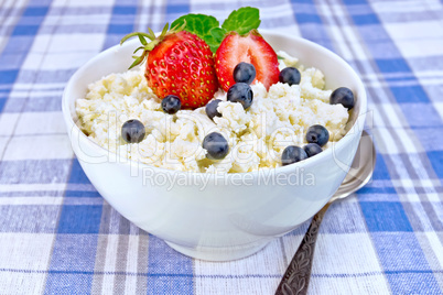 Curd in bowl with strawberries and blueberries on tablecloth