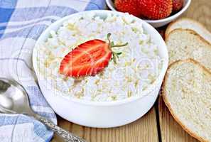 Curd with strawberries in bowl and bread on board
