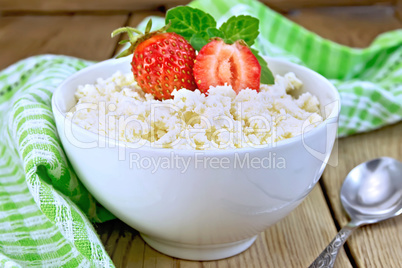 Curd with strawberries in white bowl on board