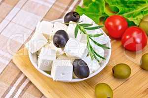 Feta with olives in bowl on fabric and board