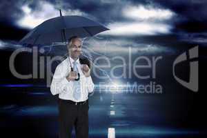 Composite image of happy businessman holding umbrella