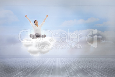 Composite image of cheering businesswoman sitting cross legged