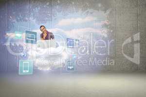 Composite image of thinking man sitting on floor using laptop an