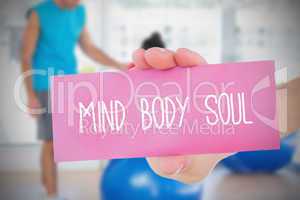 Woman holding pink card saying mind body soul